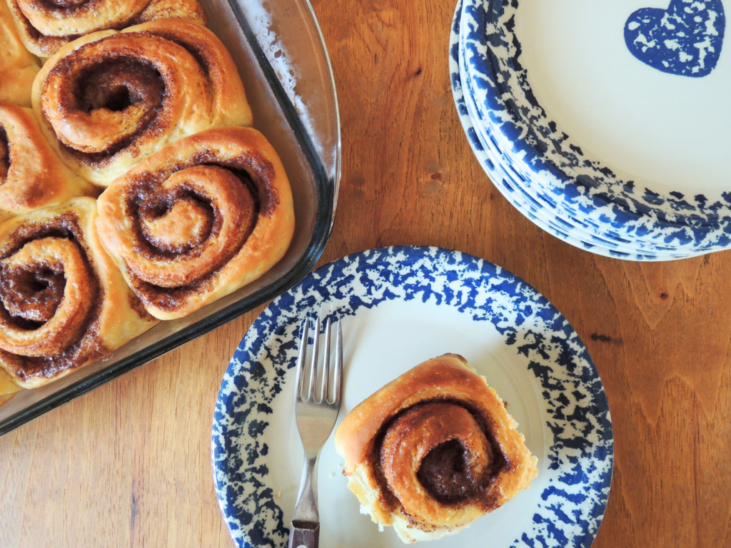 unfrosted cinnamon rolls sitting on a table with one on a plate